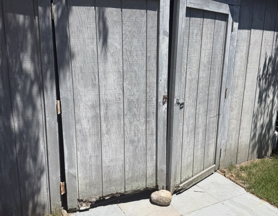 Gray vertical-board shed doors with metal hinges